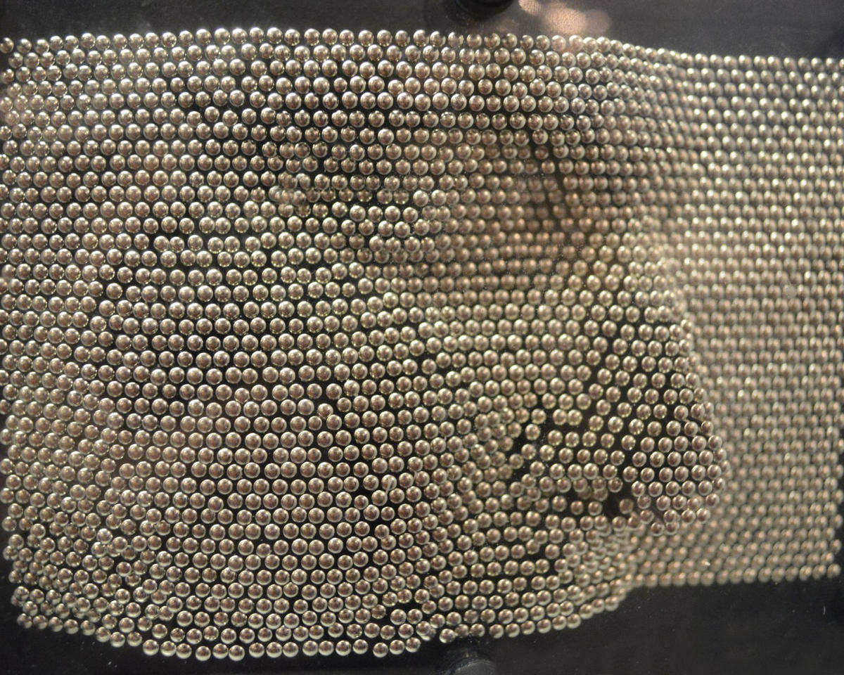 a face pressed into a pin art toy